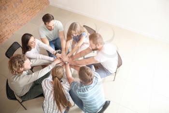Young people putting hands together at group therapy session�