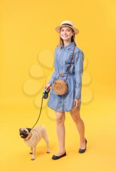 Beautiful young woman with cute pug dog on color background�