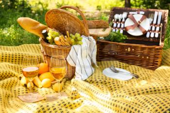 Wicker baskets with tasty food and drink for romantic picnic in park�