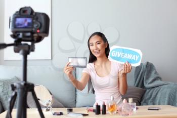 Asian beauty blogger announcing giveaway while recording video at home�