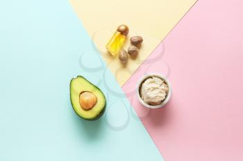 Bowl with shea butter, essential oil and avocado on color background�