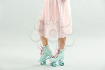 Beautiful young woman on roller skates against light background�