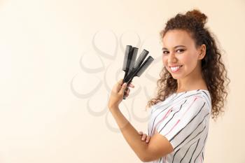 Beautiful African-American hairdresser on light background�