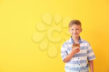 Funny little boy holding tasty toast with chocolate spreading on color background�