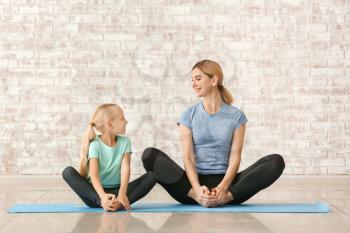 Mother with little girl doing yoga indoors�