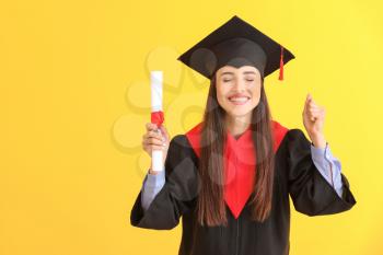 Happy female graduate with diploma on color background�
