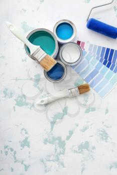 Cans of paint with supplies and palette samples on light background�