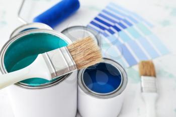 Cans of paint with brush on table, closeup�
