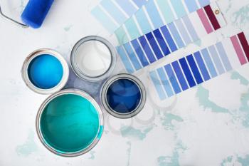 Cans of paint with palette samples on light background�