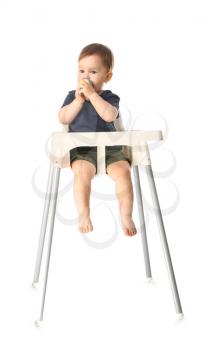 Cute little boy with nibbler sitting in high chair against white background�