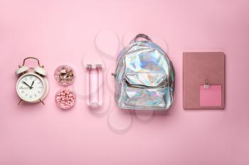 School backpack, clock, bottle of water and stationery on color background�