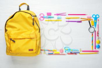 Frame made of backpack with school supplies on white wooden background�