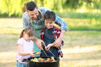 Little children with father cooking tasty food on barbecue grill outdoors�