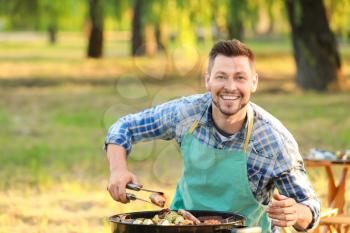 Man cooking tasty food on barbecue grill outdoors�