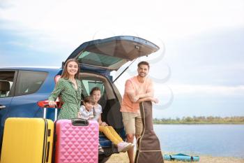 Happy family with luggage near car at resort�
