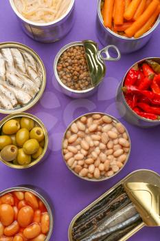 Tin cans with different food on color background�