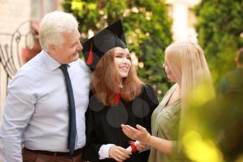 Happy young woman with diploma and her parents on graduation day�