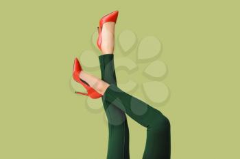 Legs of young woman in high-heeled shoes and pants on color background�