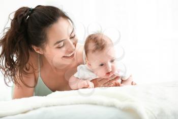 Happy mother with cute little baby lying on bed�