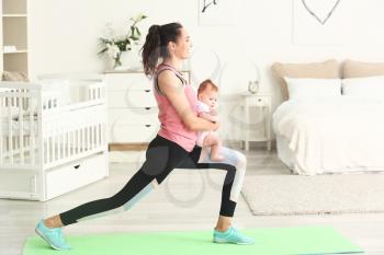 Mother practicing yoga with cute little baby at home�