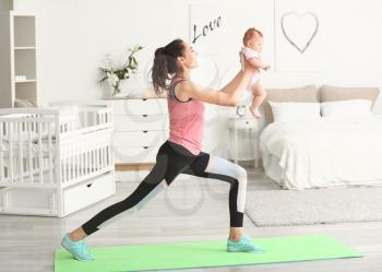 Mother practicing yoga with cute little baby at home�