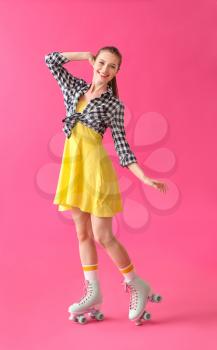 Beautiful young woman on roller skates against color background�