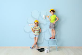 Cute little children painting wall in room�