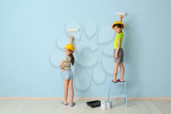 Cute little children painting wall in room�