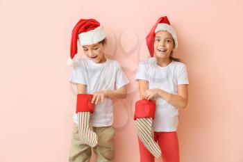 Happy little children in Santa hats and with Christmas stockings on color background�