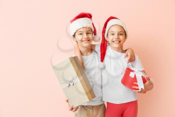 Happy little children in Santa hats and with gift boxes on color background�