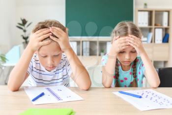 Pupils passing difficult school test in classroom�
