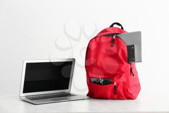 School backpack and laptop on white background�