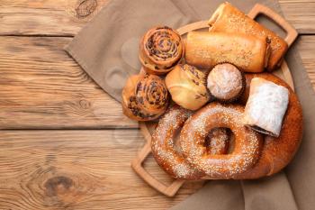 Board with tasty pastries on wooden background�