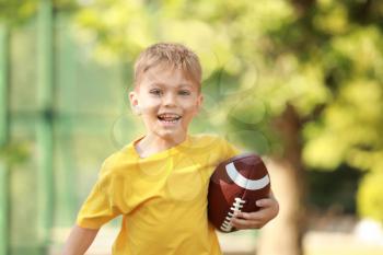 Running little boy with rugby ball in park�