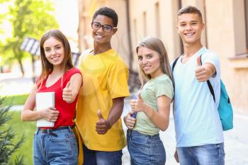 Portrait of young students showing thumb-up outdoors�