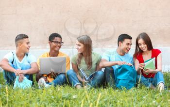 Portrait of young students sitting on grass outdoors�