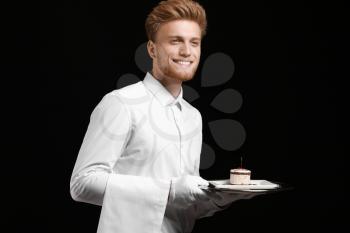 Handsome waiter with dessert on dark background�