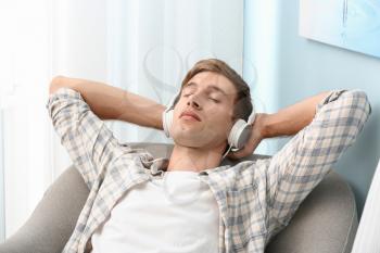 Handsome young man relaxing and listening to music at home�