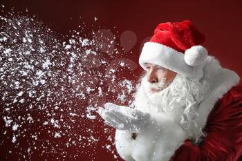 Portrait of Santa Claus playing with snow on color background�