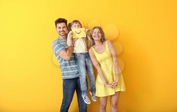 Portrait of happy family with drawn smile on sheet of paper against color background�