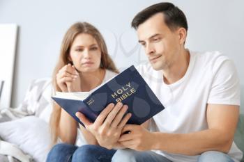 Religious couple reading Bible at home�