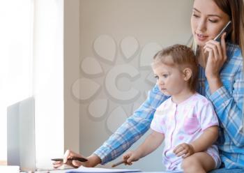 Working mother with her daughter at home�
