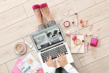 Female beauty blogger with laptop sitting on wooden floor, top view�