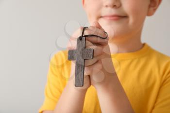 Praying little boy on light background, closeup�