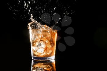 Splash of whiskey in glass on dark background�