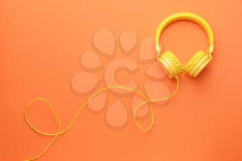 Modern headphones on color background�