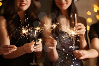 Happy women with Christmas sparklers and glasses of champagne at party�