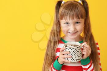Cute little girl drinking hot chocolate on color background�