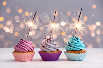 Tasty Birthday cupcakes on table against defocused lights�
