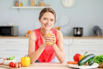 Young woman drinking healthy juice in kitchen. Diet concept�